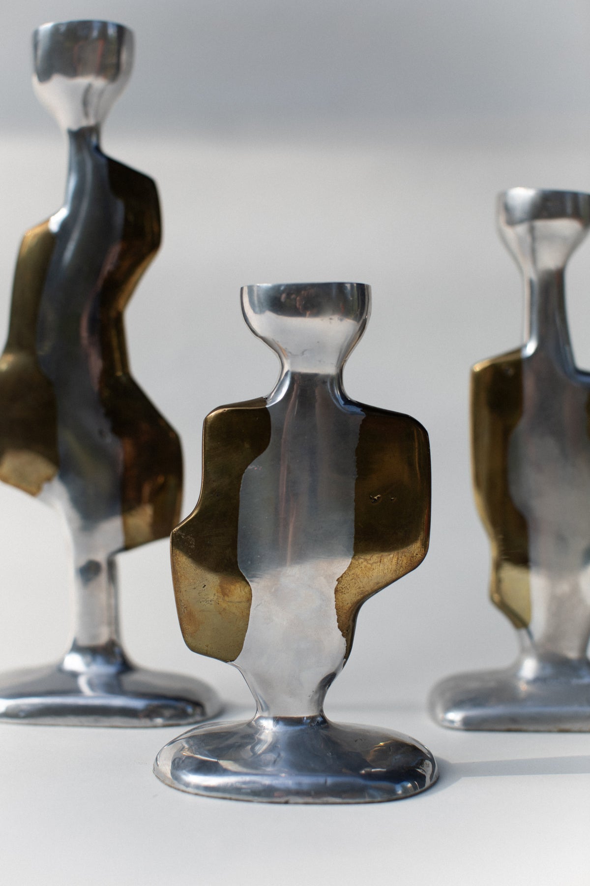 Set of three Brutalist Candleholders by Out For Lunch, featuring metallic abstract, sculptural forms in silver and brass tones, displayed on a light background.