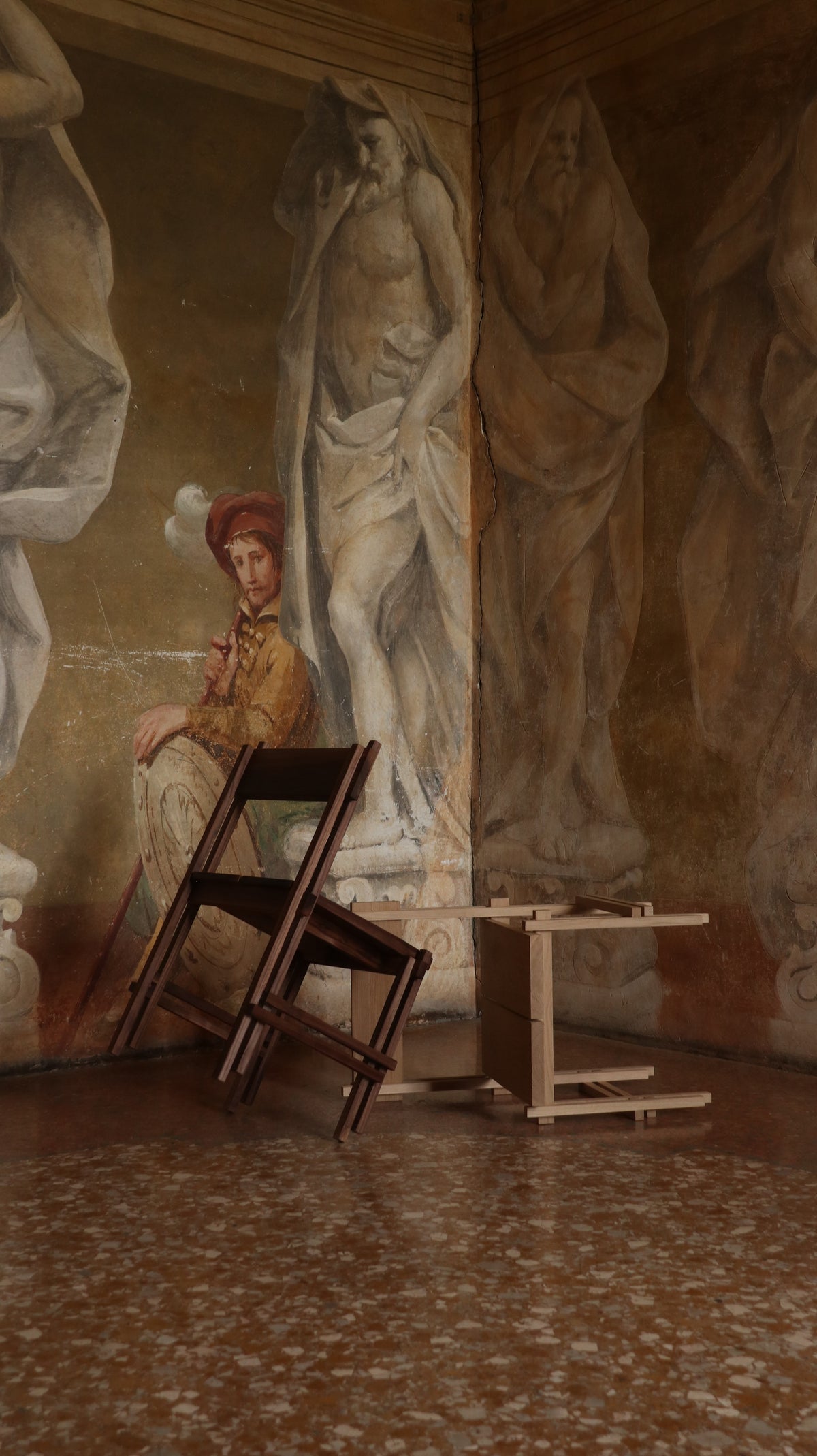 Wooden stackable chairs arranged in corner with classical frescoes