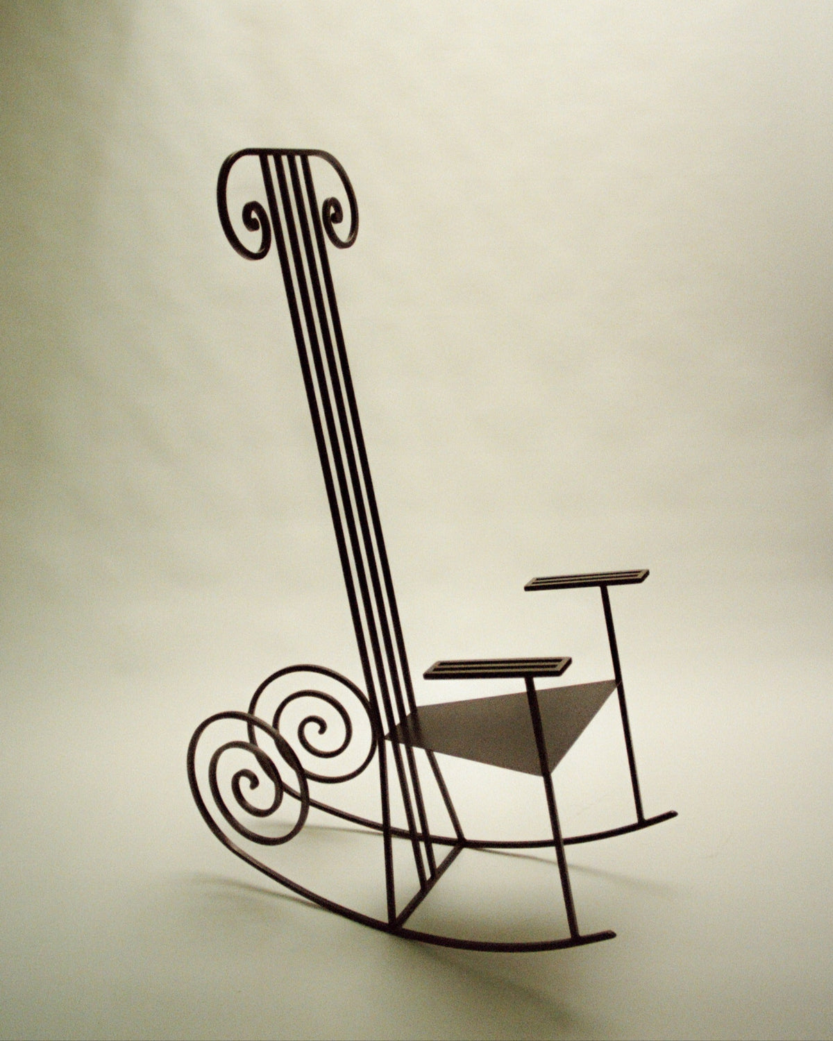 Musical note-inspired iron rocking chair with curved scrollwork