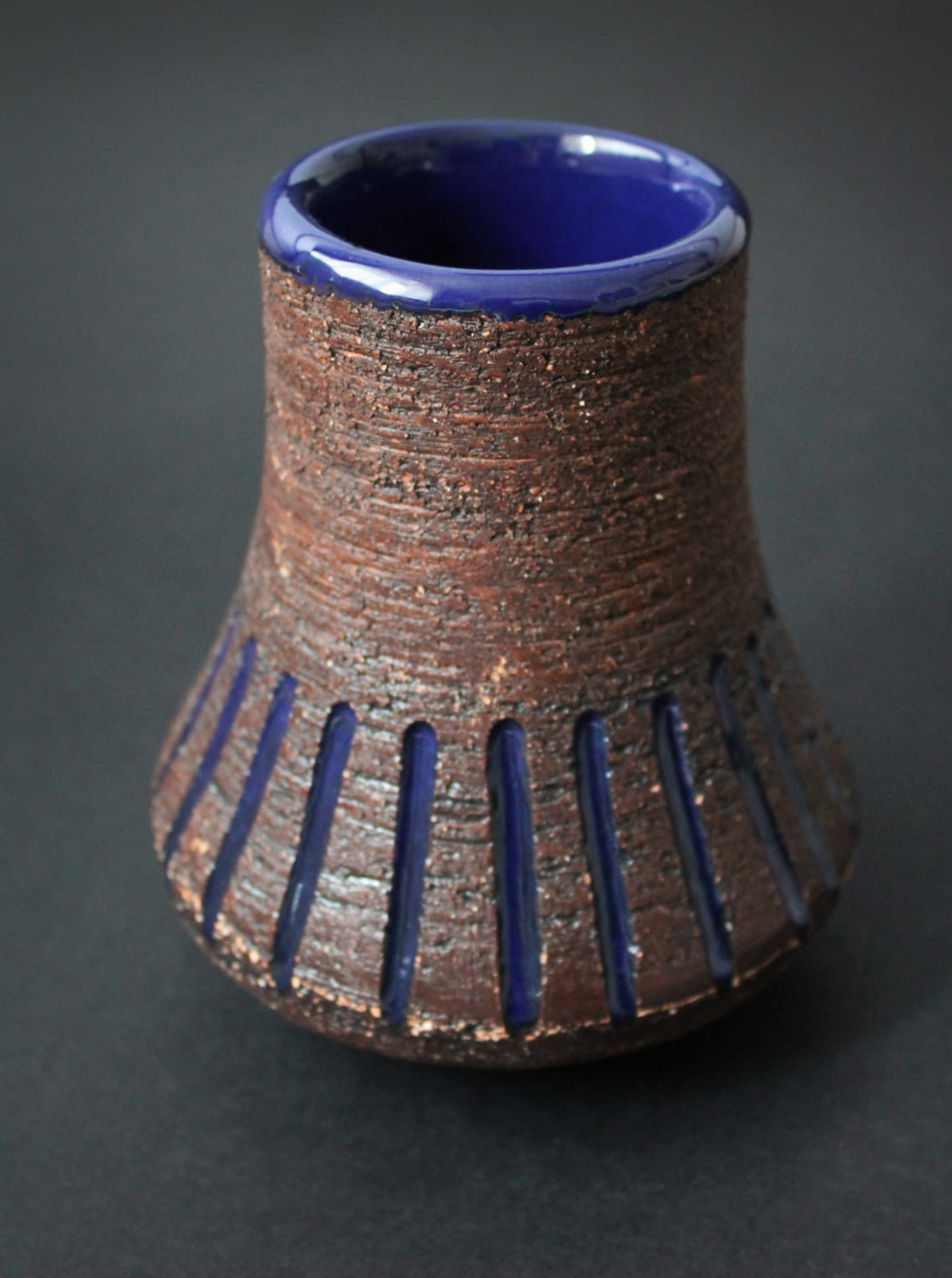 Textured ceramic vase with cobalt blue interior and striped pattern
