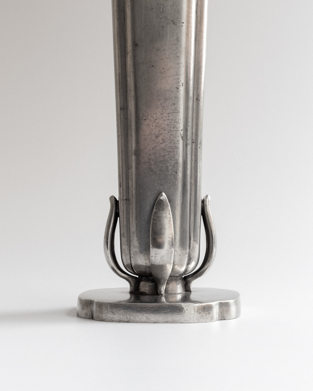 Close-up detail of pewter vase base with decorative metal accents