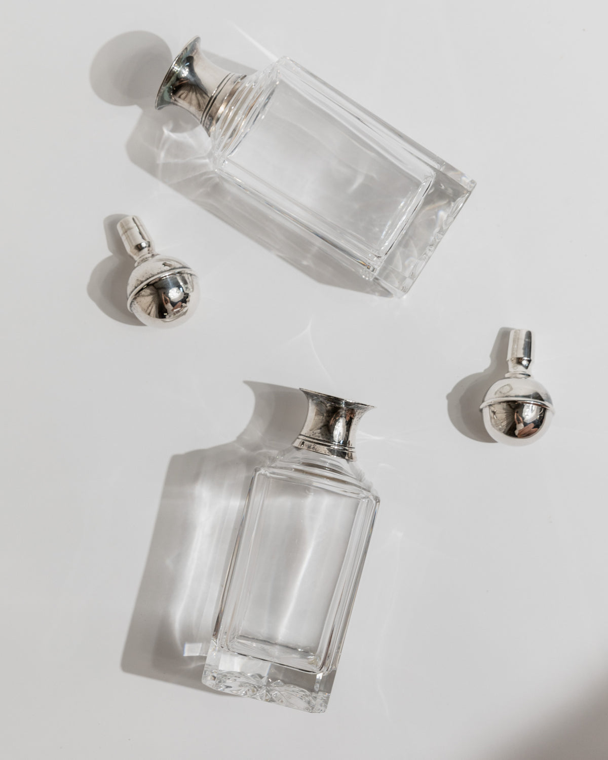 Empty crystal decanters with silver caps displayed separately