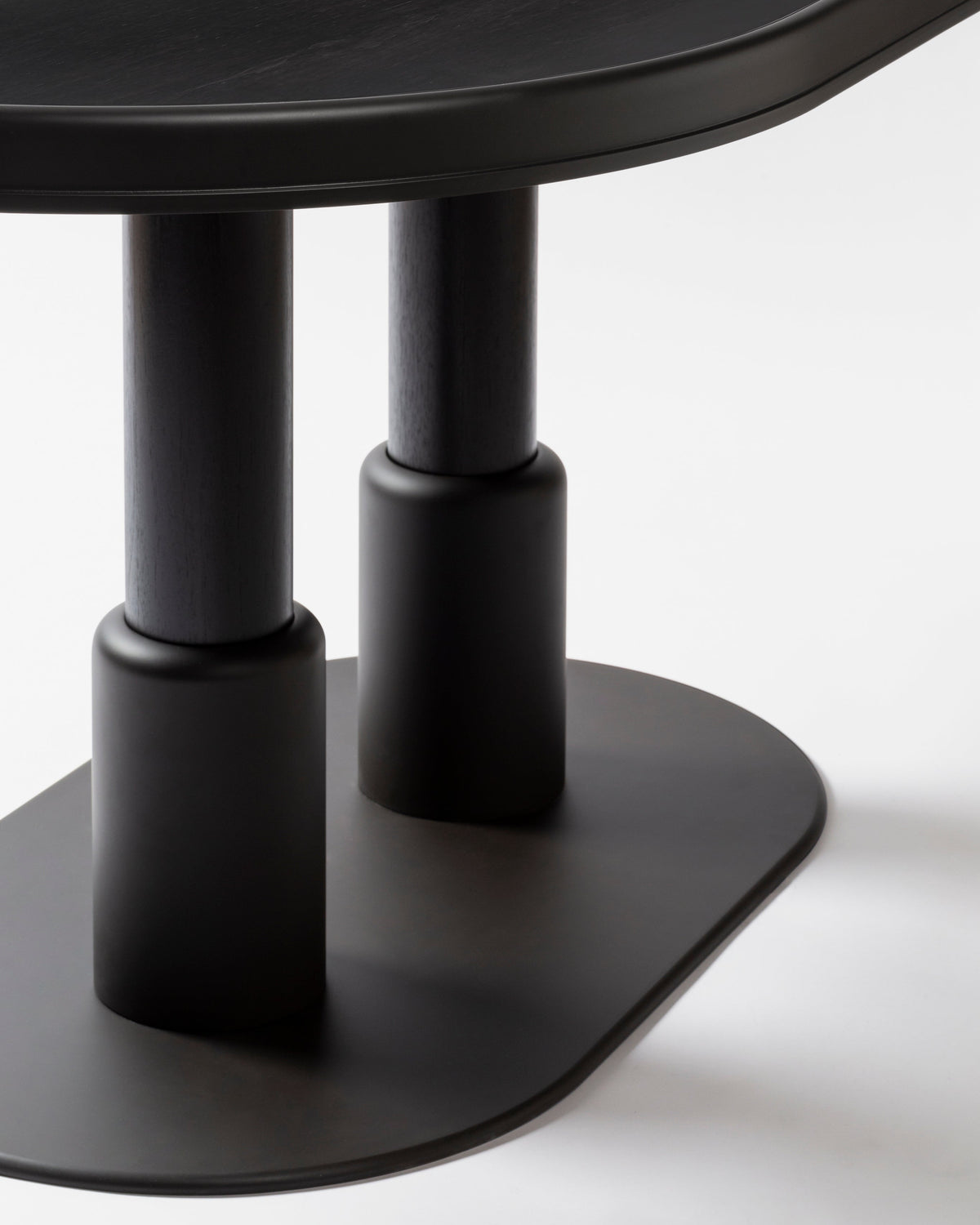 Close-up detail of black cylindrical legs on oval table base