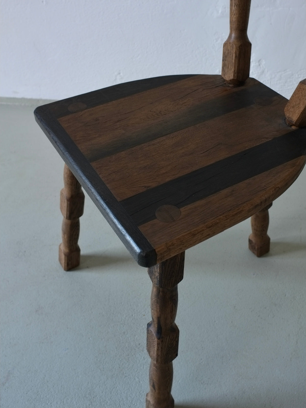 Close-up detail of walnut dining chair seat with black accent stripes