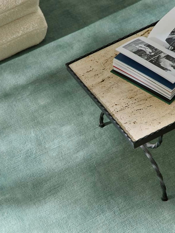 Hand-woven Rug in New Zealand Wool. Pale Blue — side angle with coffee table and books