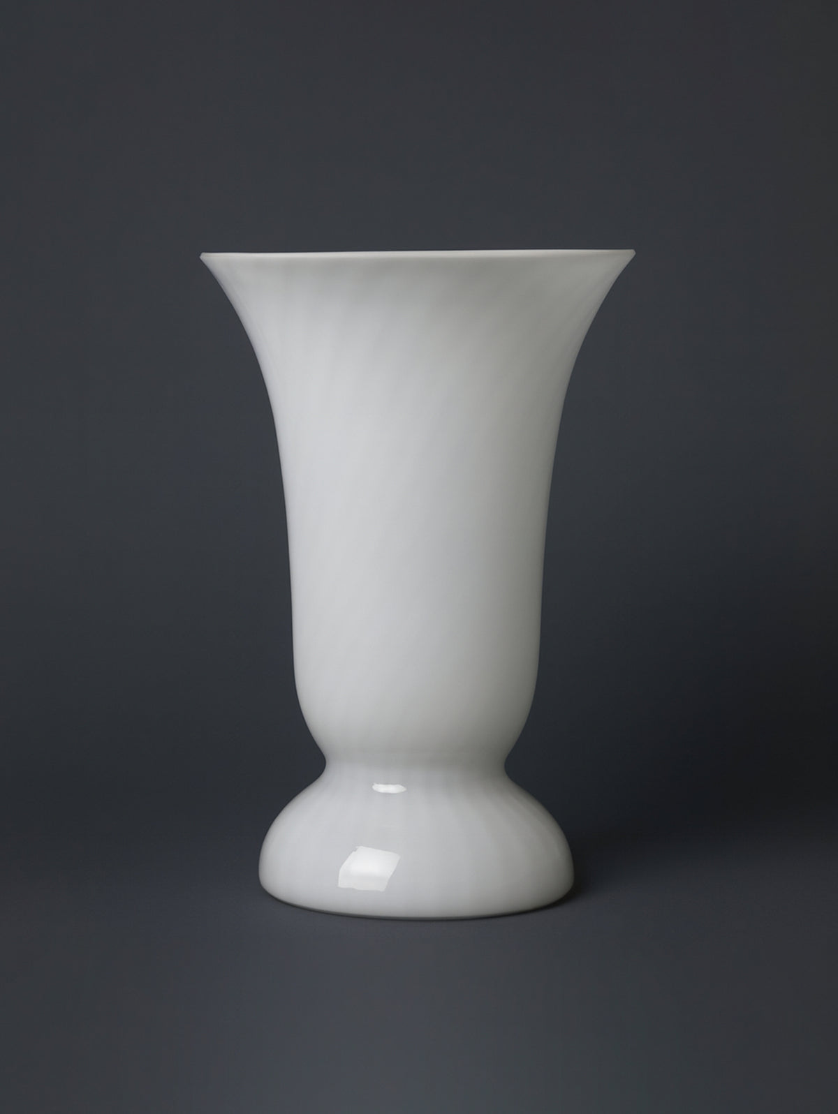 The Dodo Vintage Mid Century Murano Swirl Glass Table Lamp features a glossy white goblet-shaped base with a flared mouth and swirl pattern, inspired by classic designs, shown against a dark gray background.