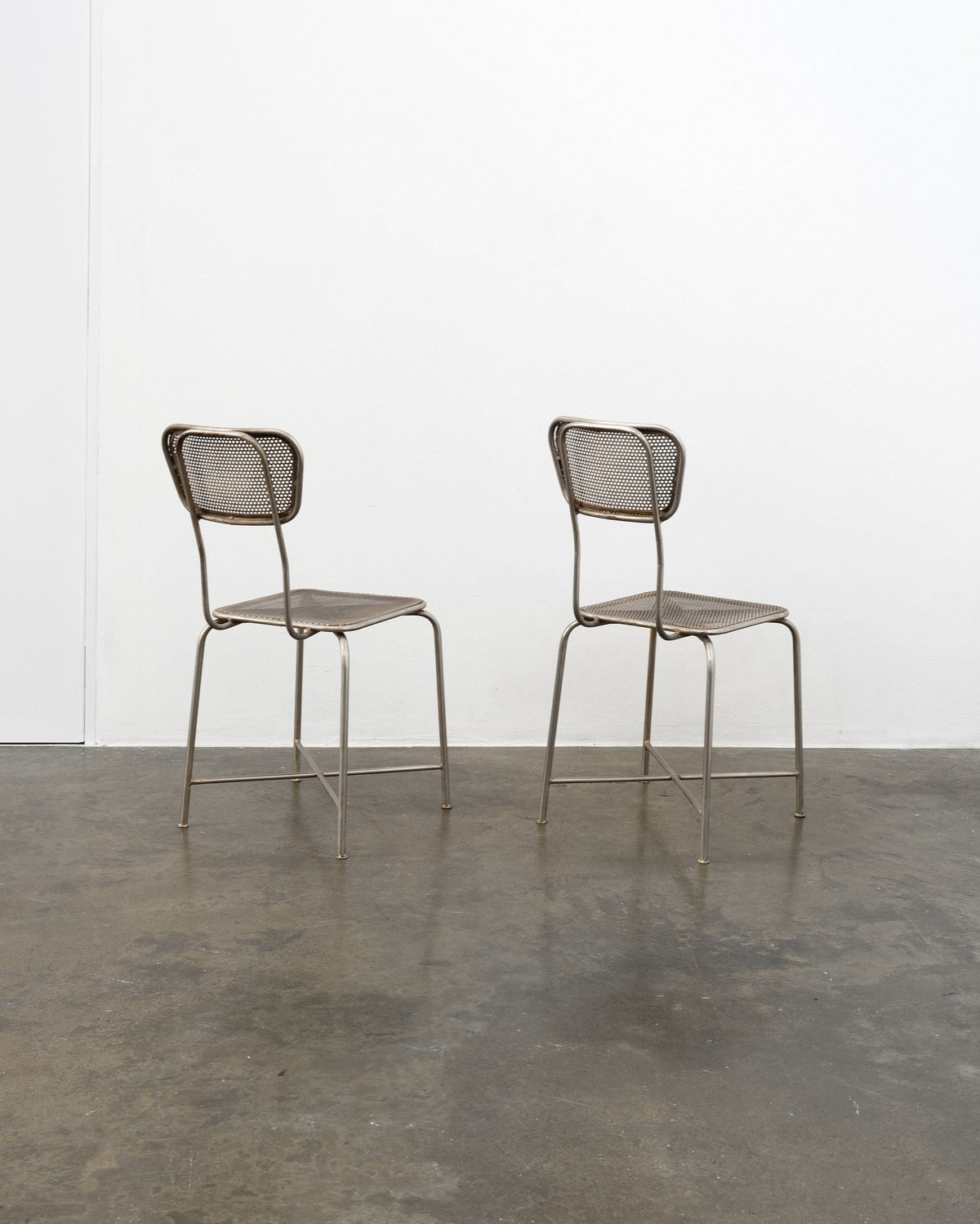 Pair of vintage perforated metal chairs with cane webbing seats