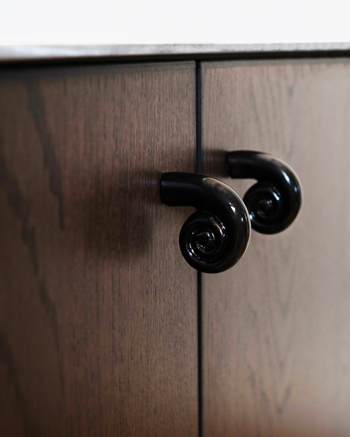 Noelle Knob - Antique Brass — side angle on dark wood cabinet