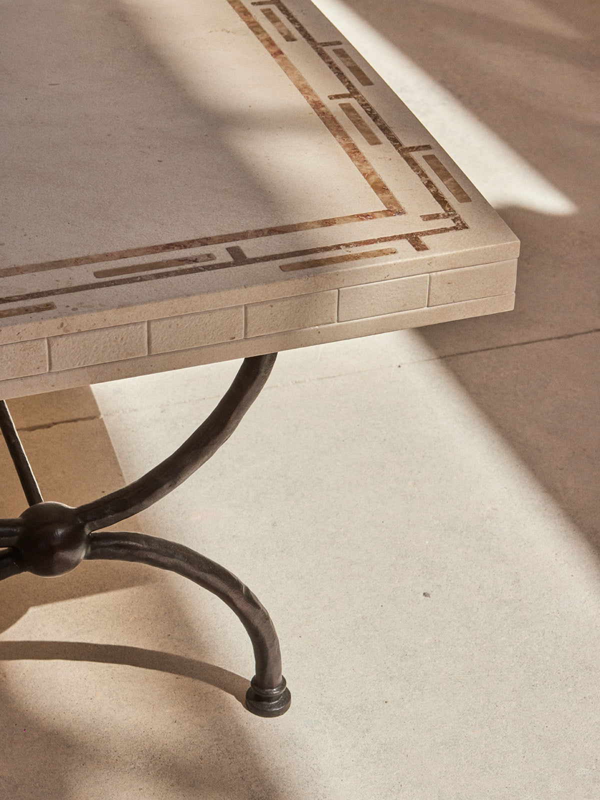 Greek Symposia Dining Table — side angle showing stone top and metal legs