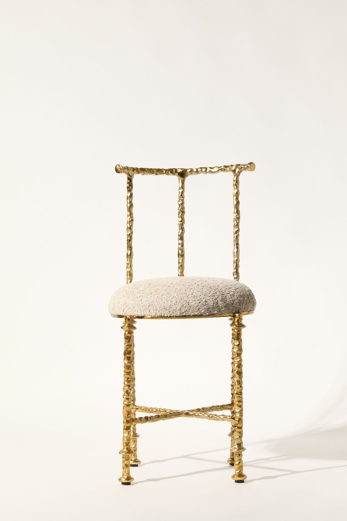 Aurelius' Cast Aluminum Chair — front view with textured gold finish and soft seat