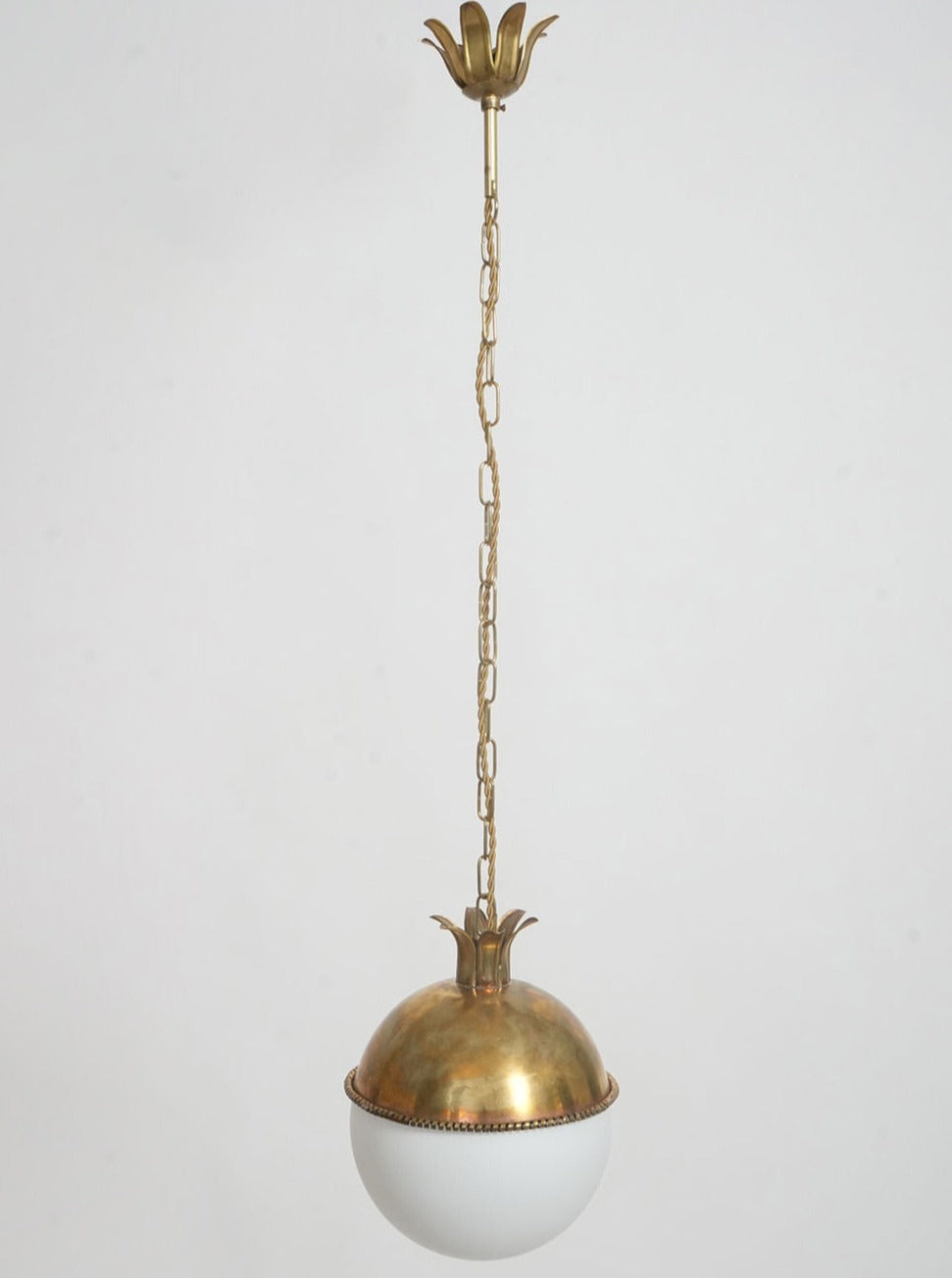 The Granada Ceiling Pendant Lamp by Barracuda Interiors features a decorative chain, dome-shaped brass top, and a white glass globe shade, elegantly suspended against a plain white background.