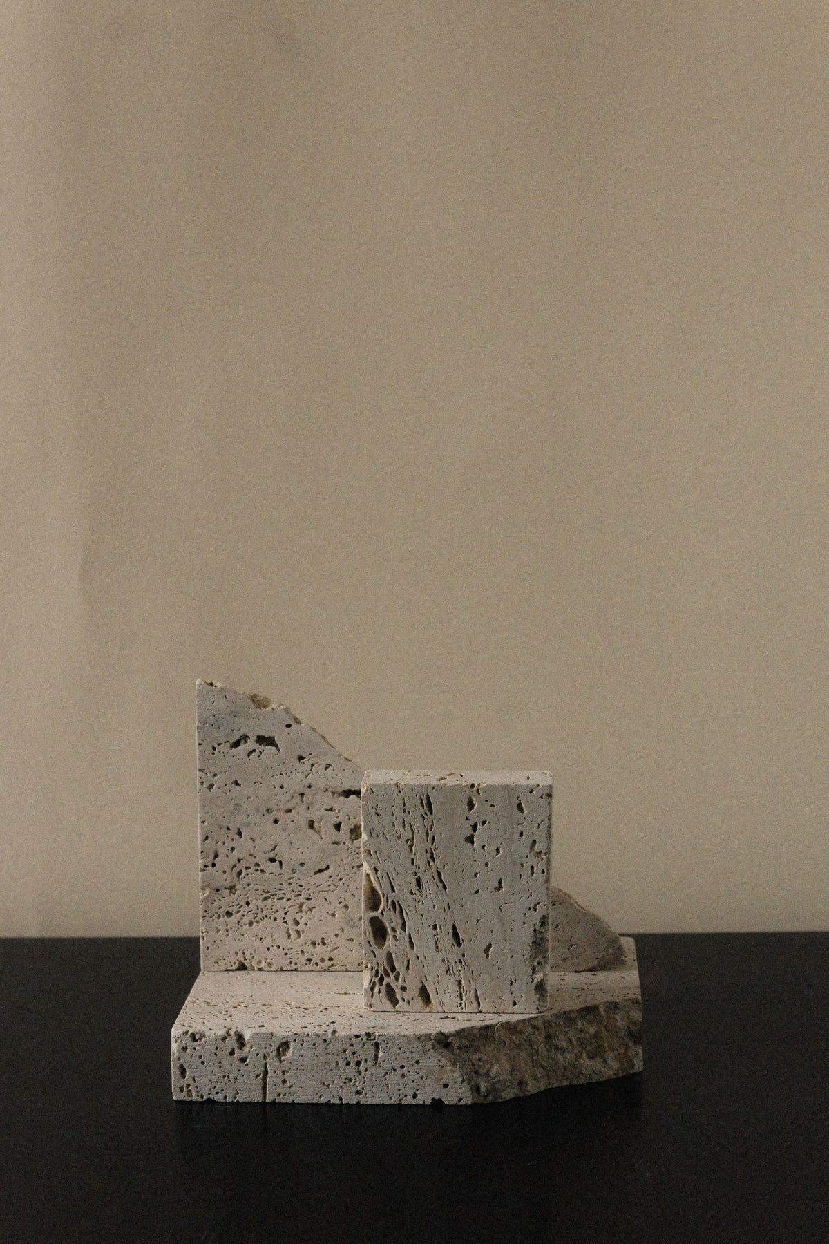 Monument I - Handmade Travertine Marble Bookstand — side angle on black surface