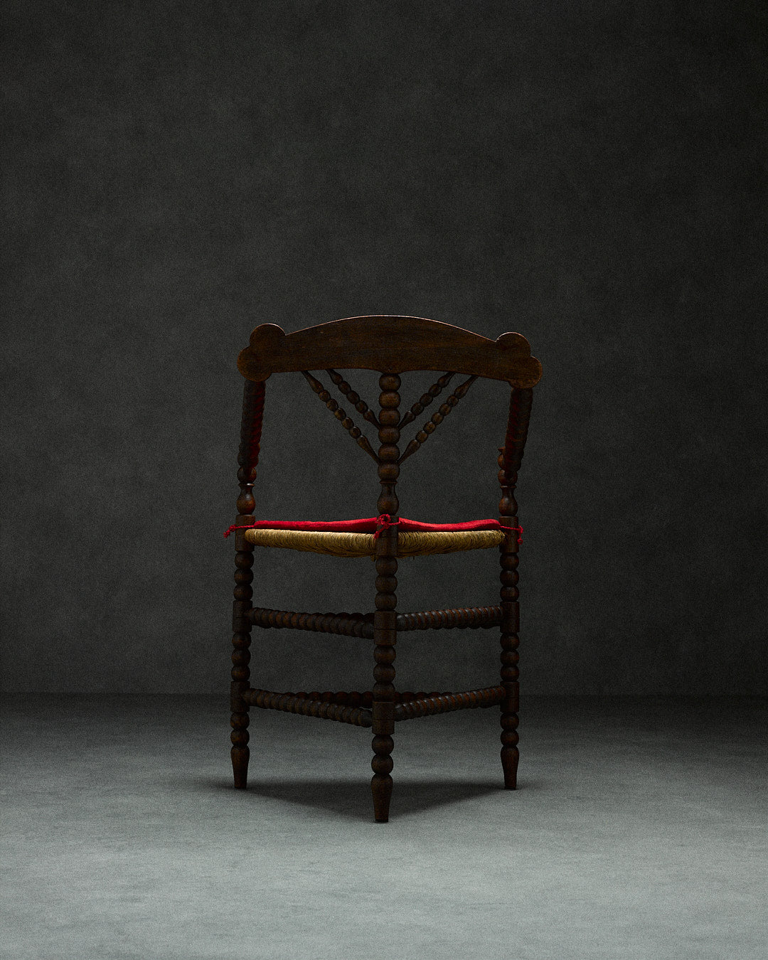 triangular bobbin chair — back view highlighting wooden texture and red seat