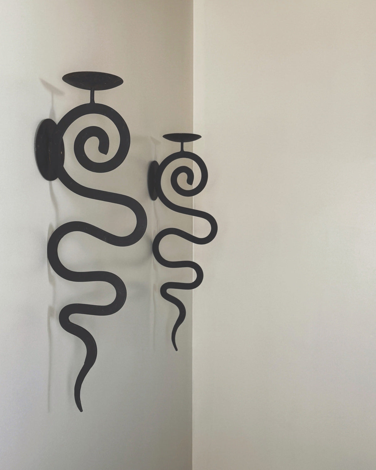 Black wrought iron wall sconces with spiral design and candle holders