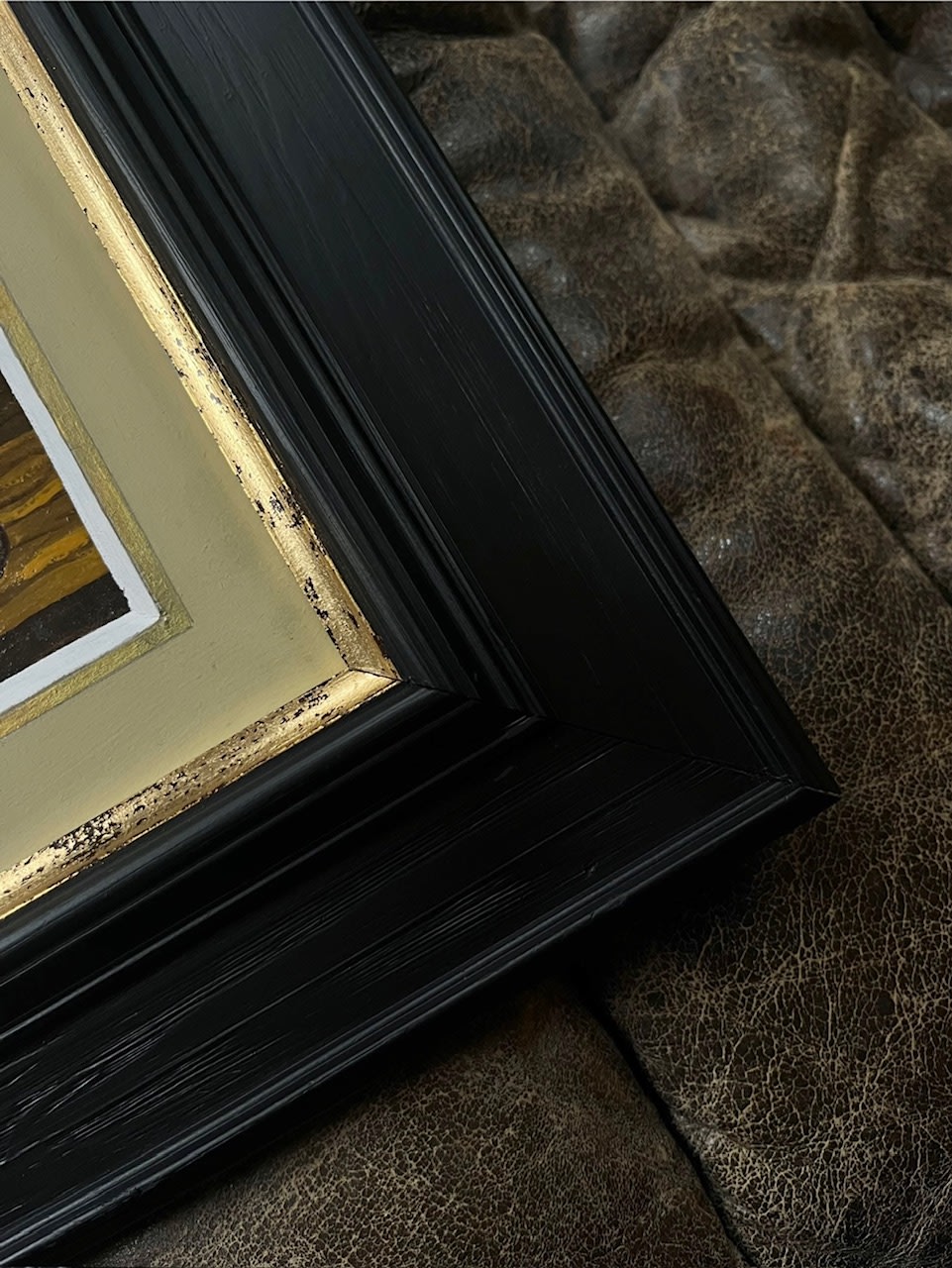 Detail of ornate black and gold frame corner with stone backdrop