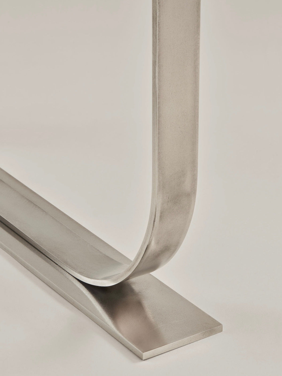 Serge Side Table, stainless steel — close-up of curved metal base
