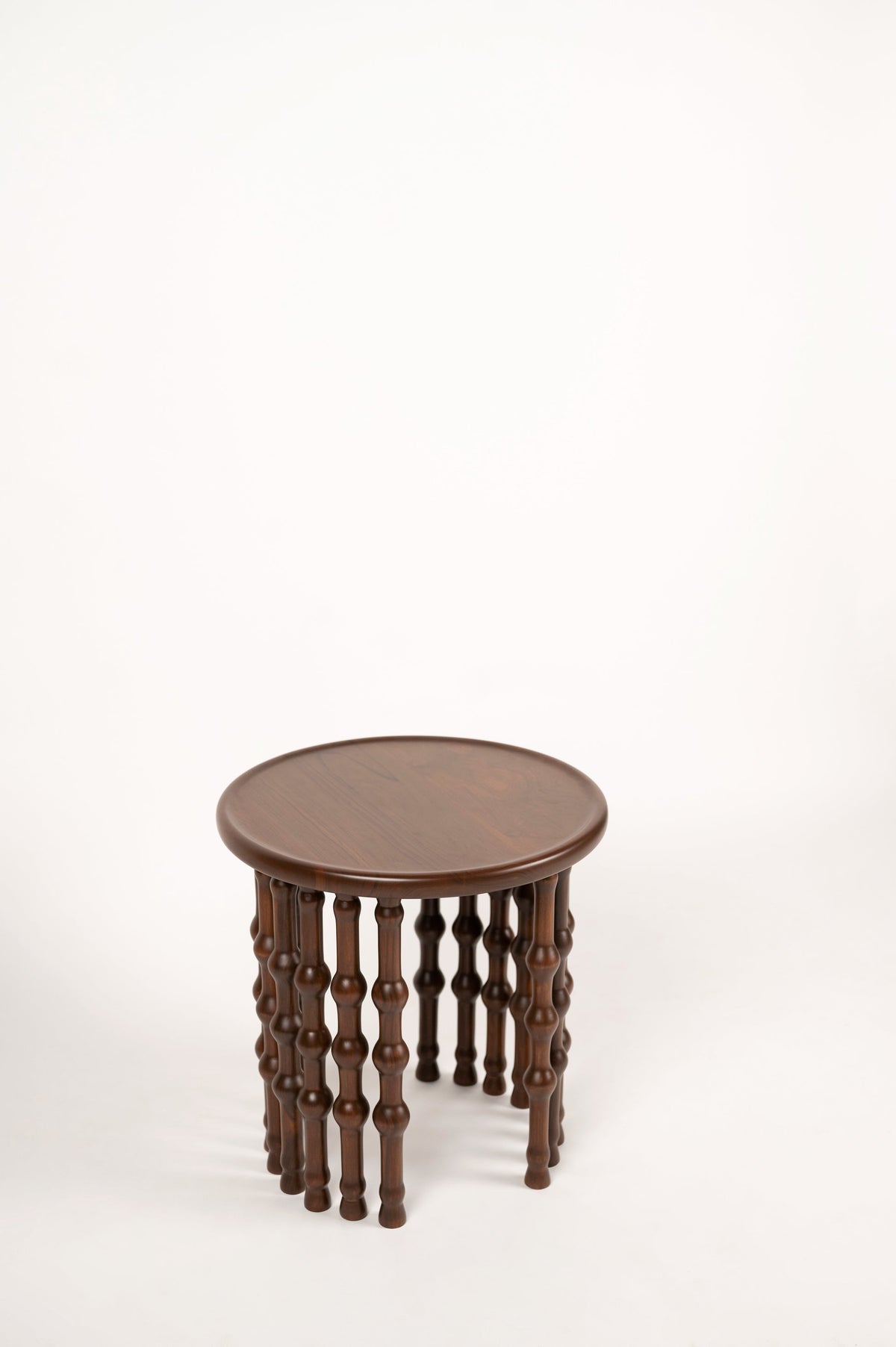 Arcus Side Table — top view of round walnut surface with turned legs