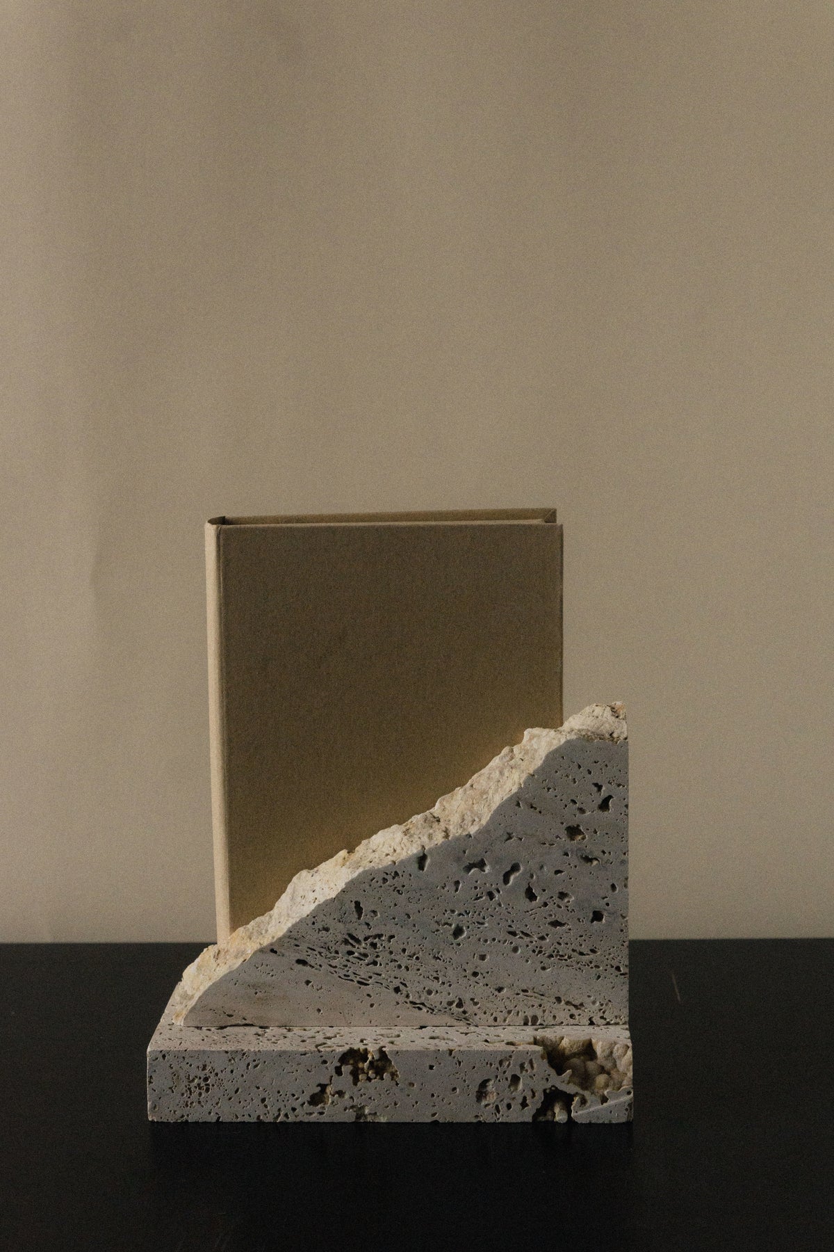 Monument I - Handmade Travertine Marble Bookstand — angled view on dark surface