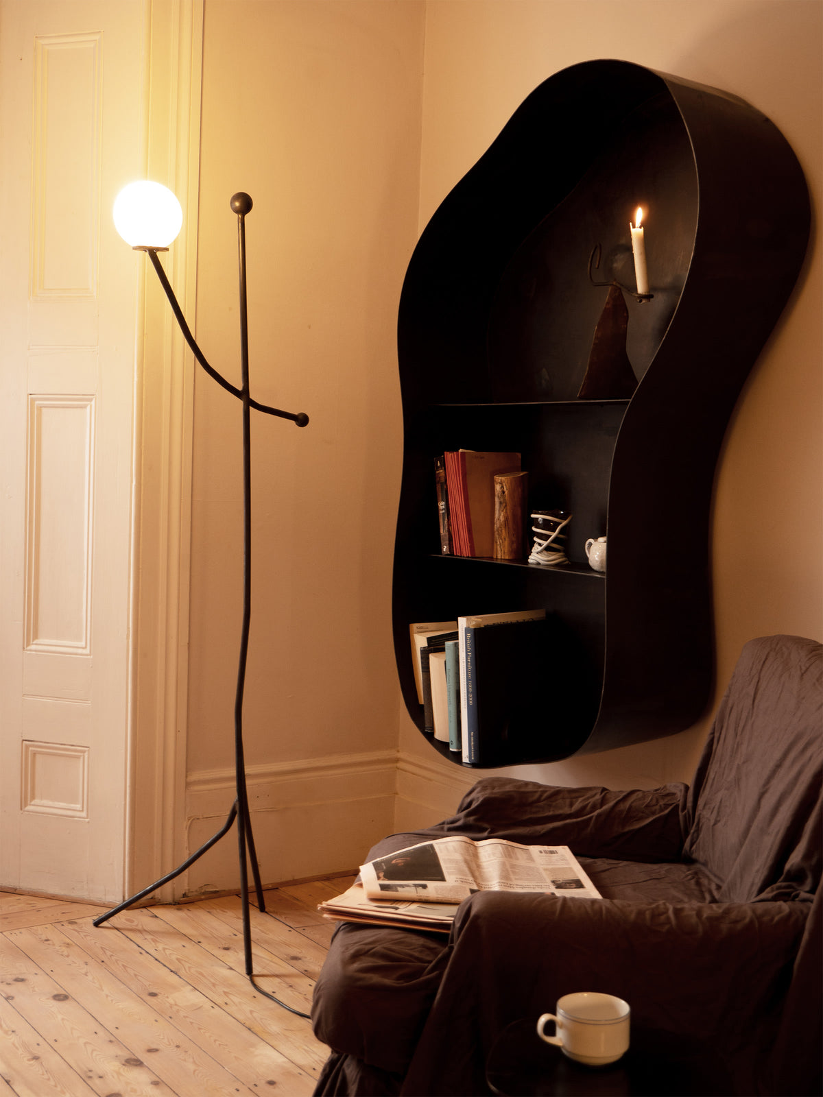 Modern black floor lamp with spherical white globe in cozy reading nook