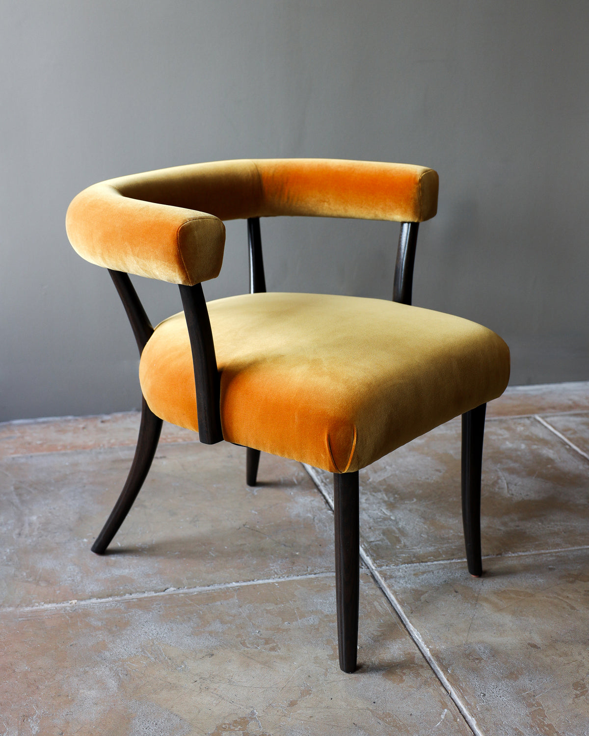 Josef dining chair with curved orange velvet upholstery and black legs