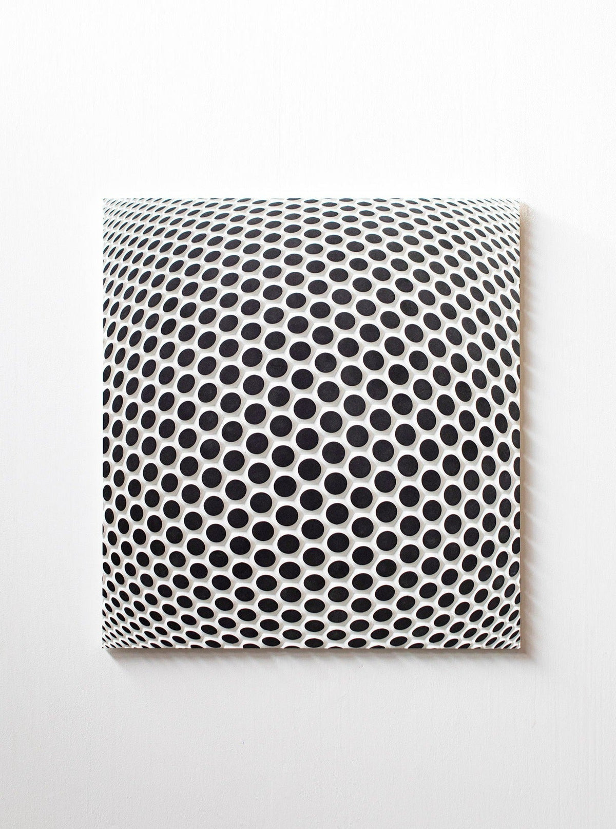 Ommatidium by Studio Arno Hoogland is a square canvas featuring a black and white optical illusion of expanding circles, creating a three-dimensional, dome-like effect on any plain white wall.