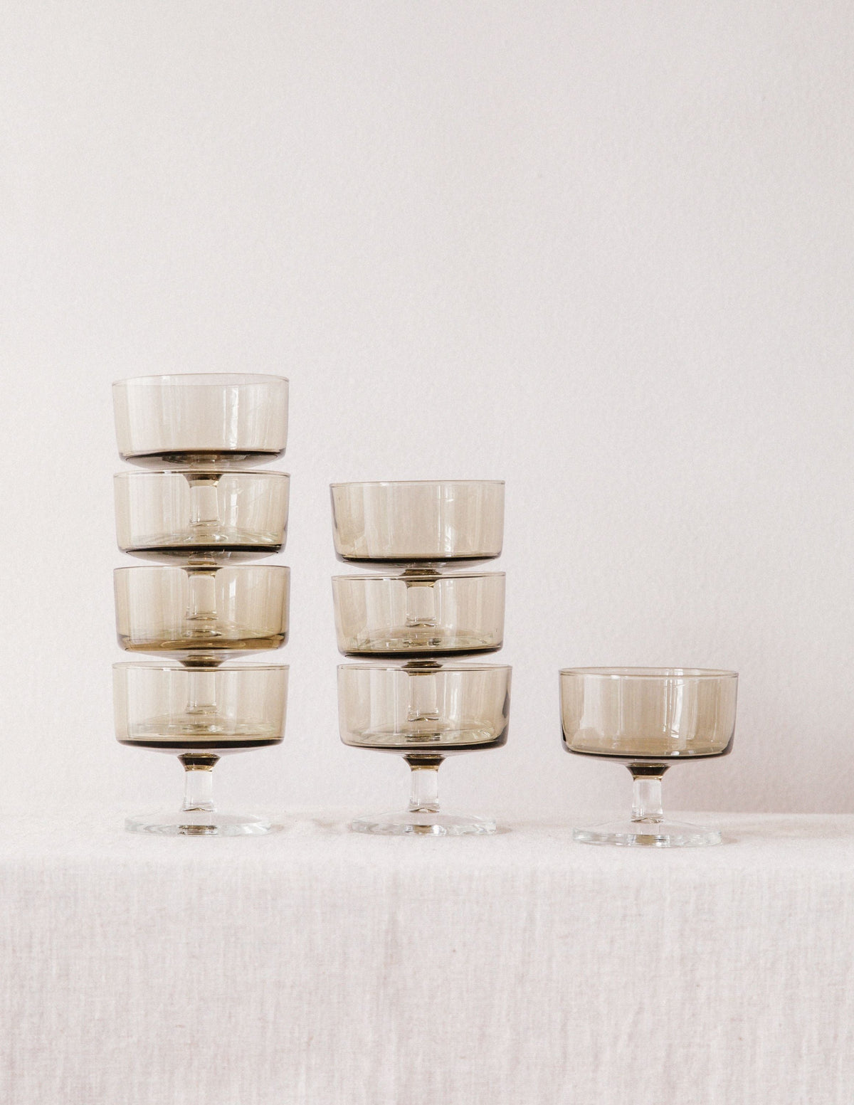 Stack of smoked glass champagne coupes showing elegant stemware design