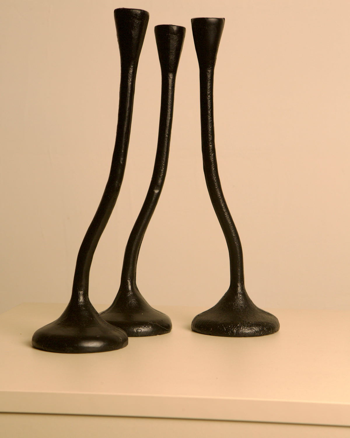 Set of 3 "Twisted" Candleholders in Black Cast Aluminum, 80s — angled view on light-colored surface