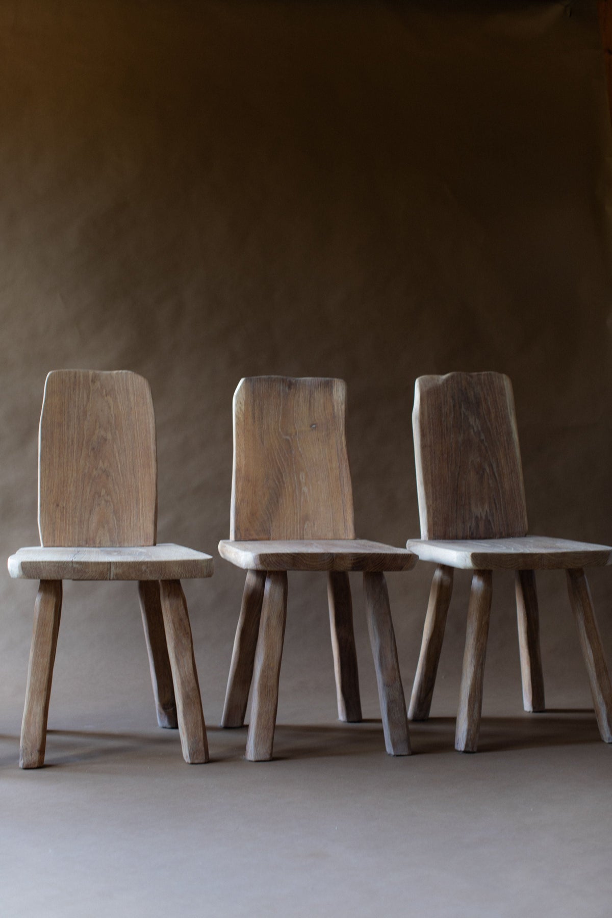Three wooden dining chairs with natural oak grain and simple legs