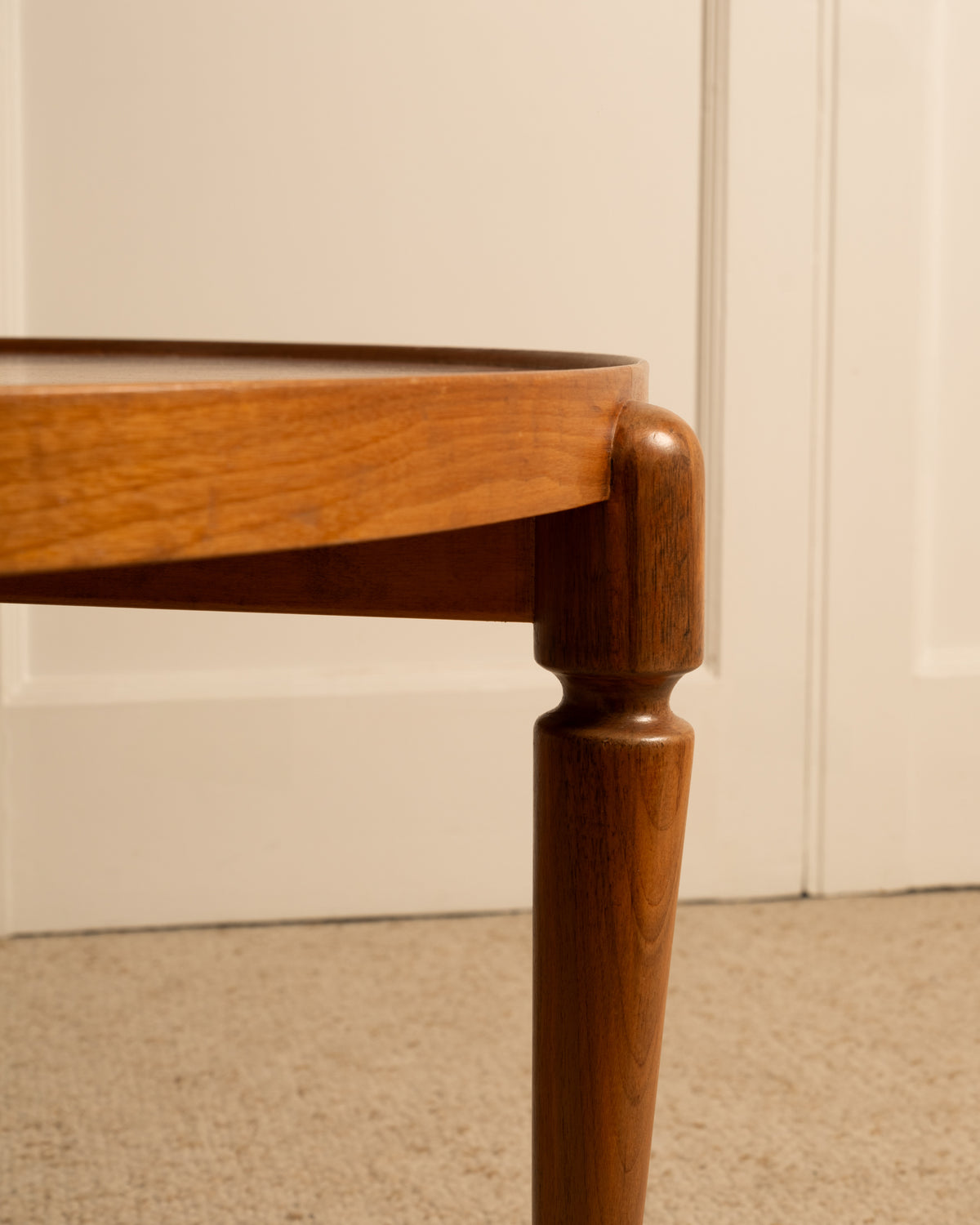 Corner detail of circular teak side table showing turned leg joint