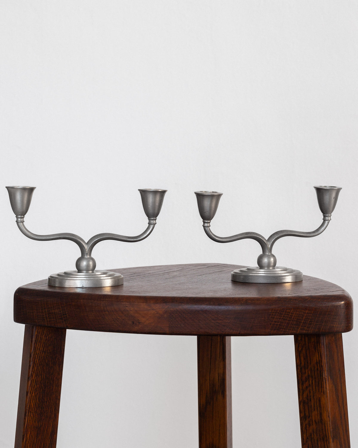 Pair of Pewter Candelabras by Just Andersen, Denmark, 1930s-40s — angled view on wooden stool