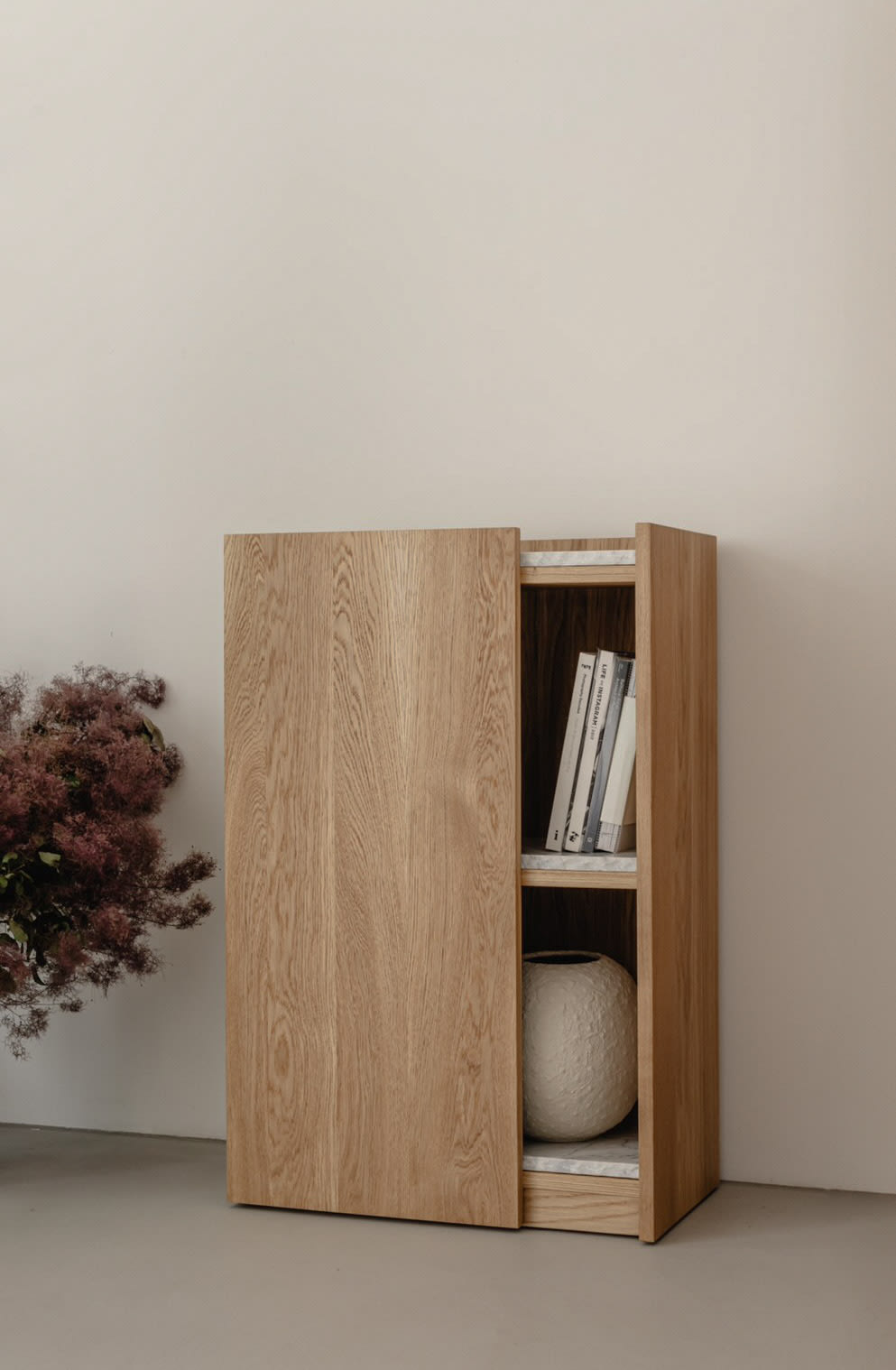 PAVO oak cabinet with sliding door open revealing books and decor