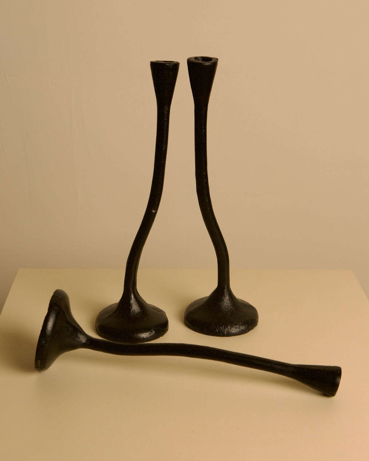 Set of 3 "Twisted" Candleholders in Black Cast Aluminum, 80s — side angle showing three candleholders on neutral background