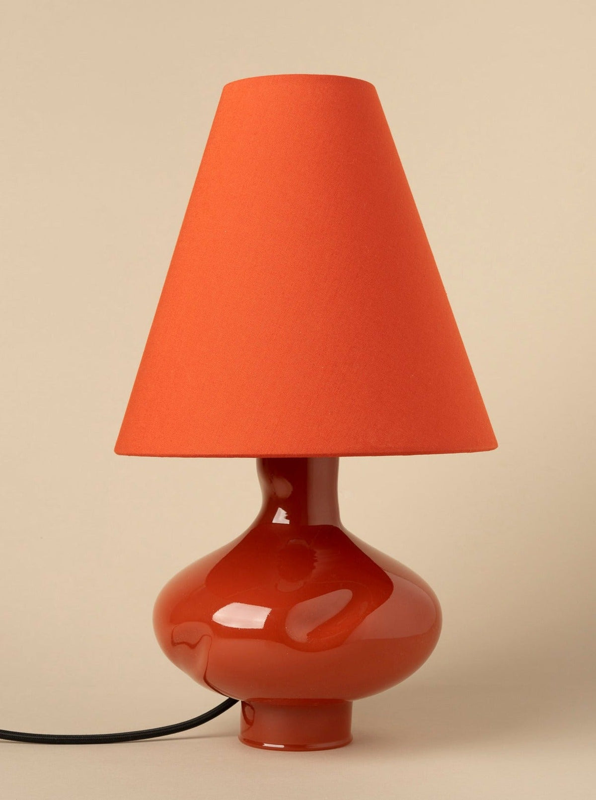 Dark red ceramic lamp base with orange conical shade, side view