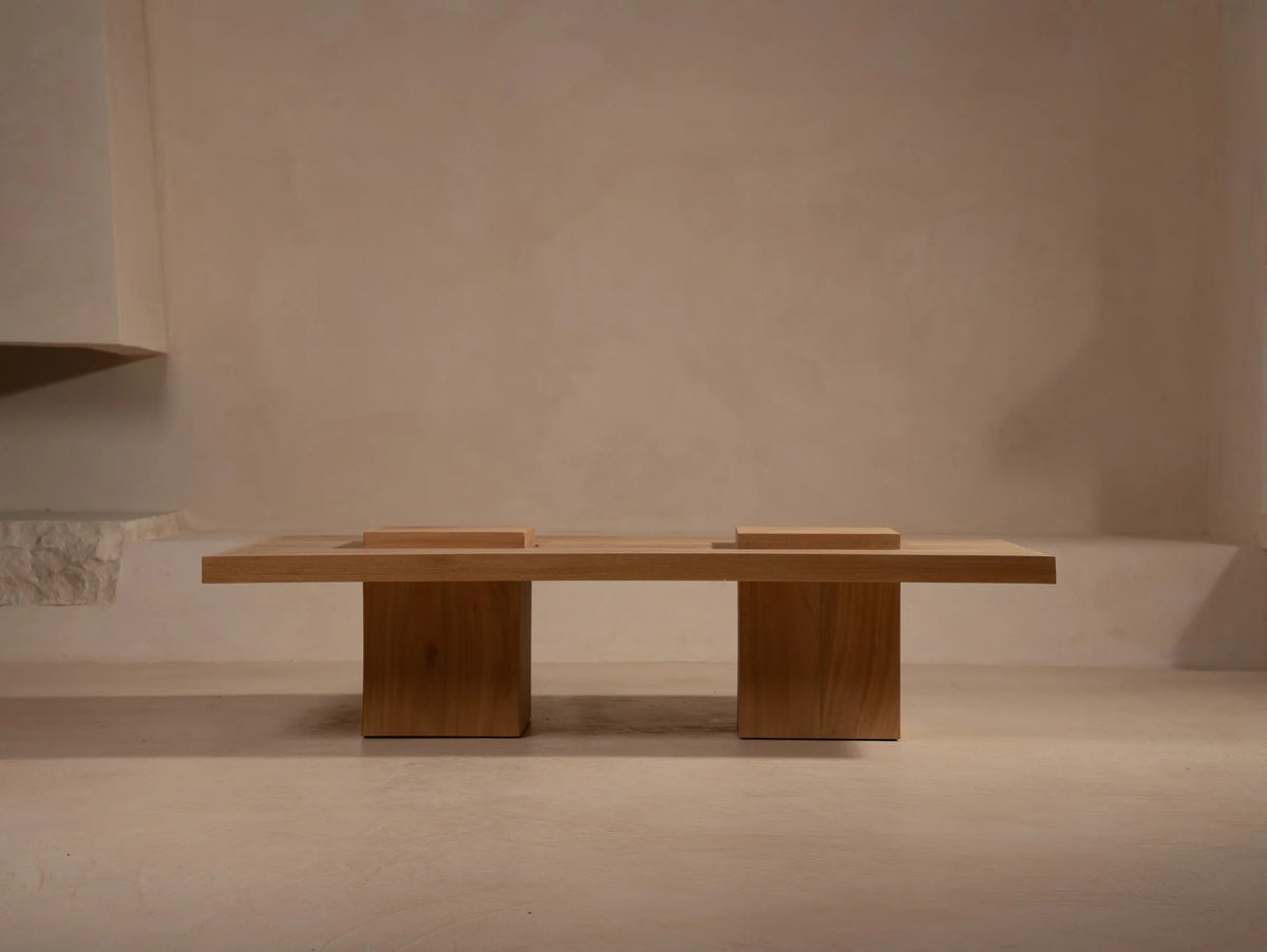 Cendra wood coffee table with dual pedestal base on neutral floor
