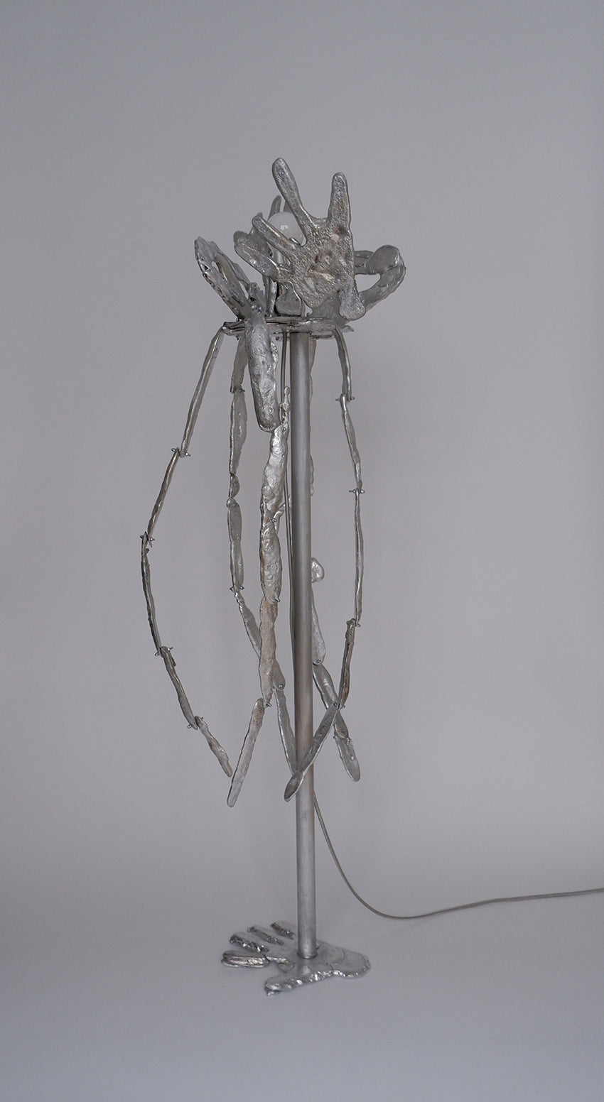 Contemporary silver metal floor lamp with sculptural hand-form top