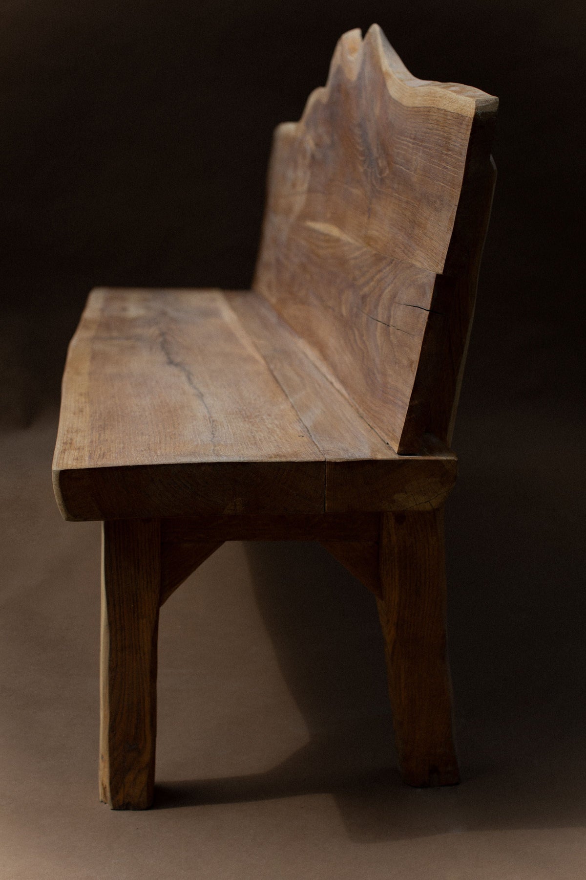 Raw oak brutalist bench with sculptural backrest profile view