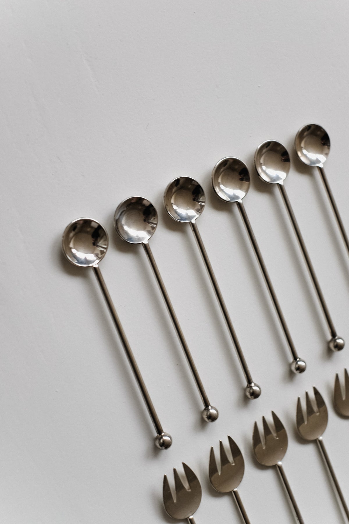 Silver-Plated Cutlery Set — side angle of spoons and forks on white surface