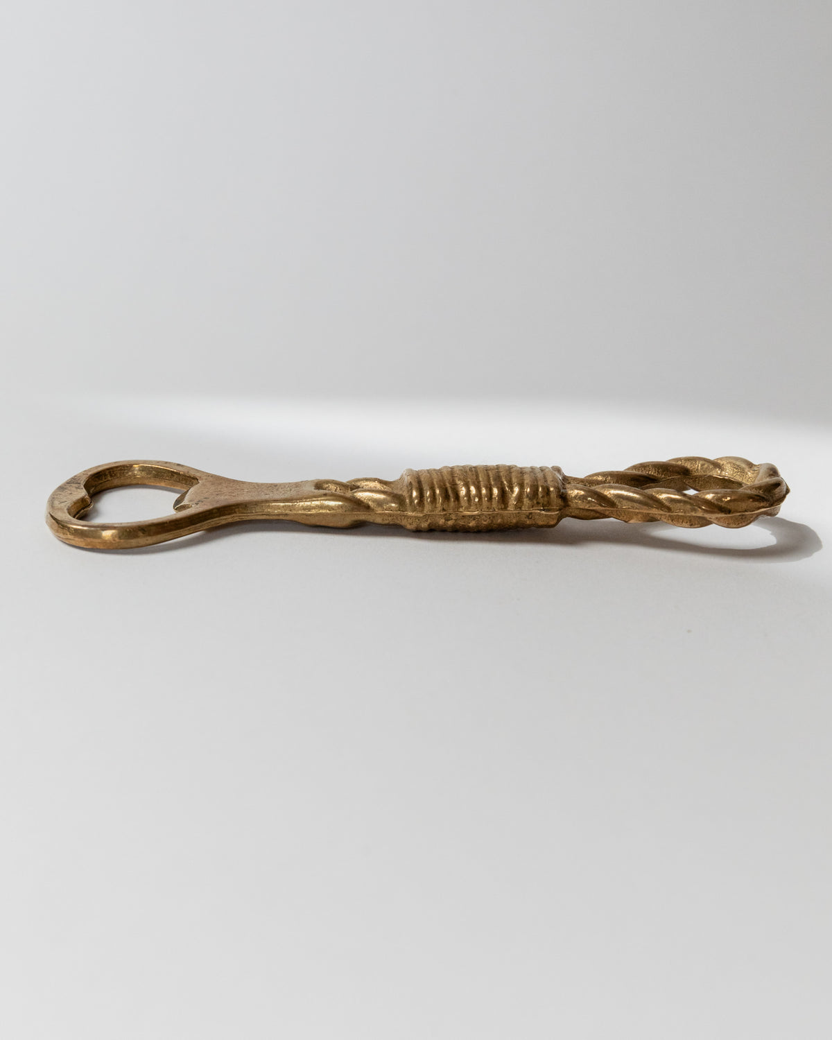 Brass bottle opener side profile view showing decorative ribbed handle Italy 1960s