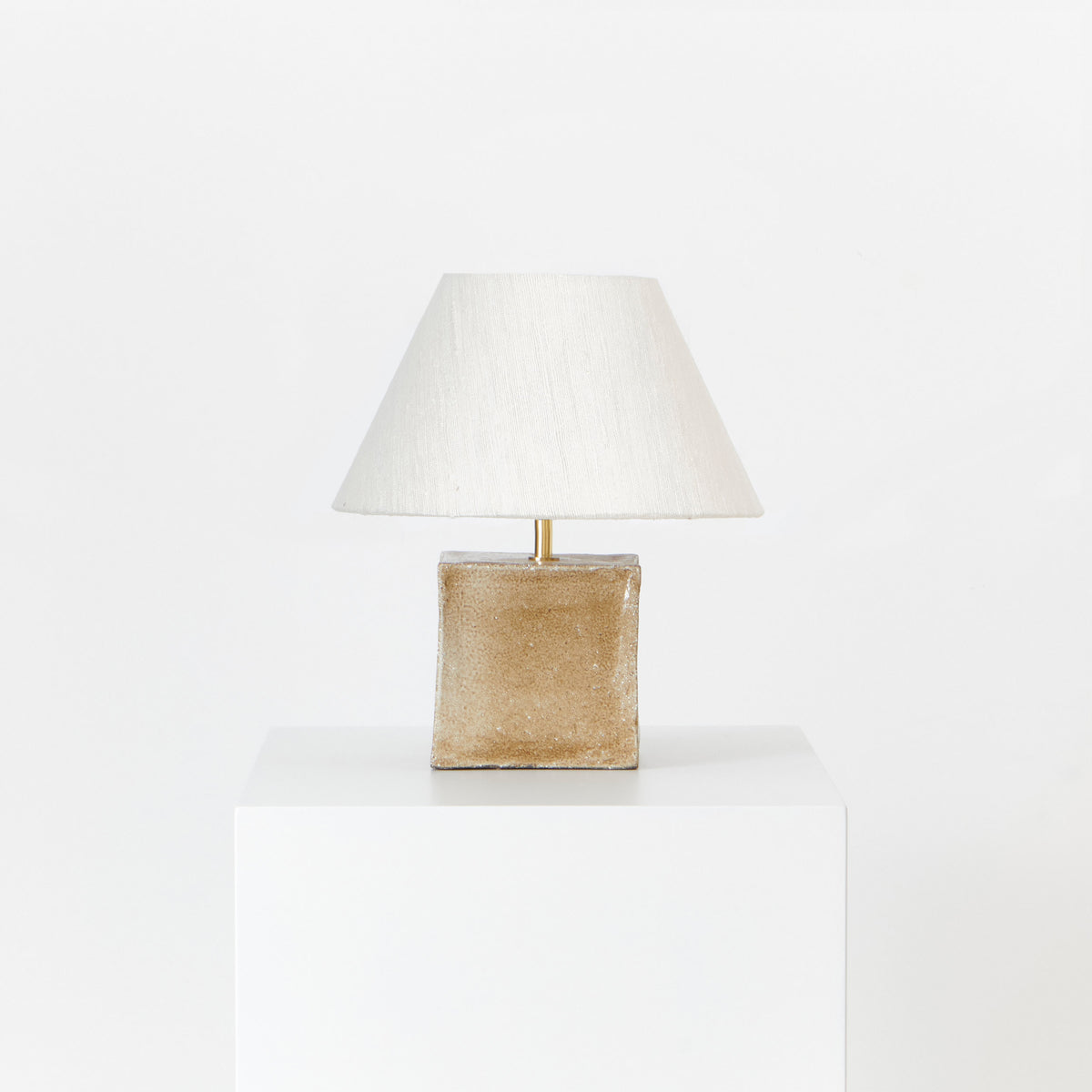 Arouca Table Light Brown Sugar — side angle of lamp on white pedestal