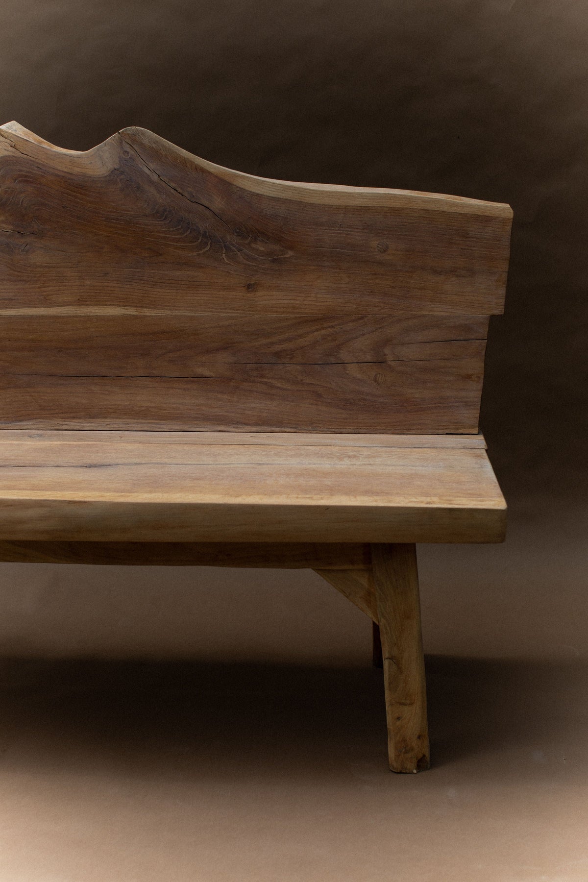 Raw wood brutalist bench with sculpted backrest and natural grain details