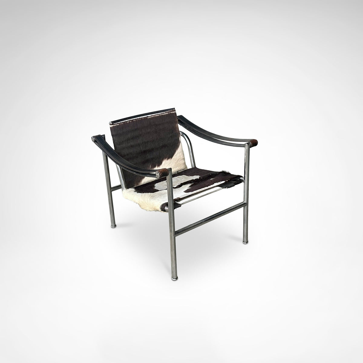 Three-quarter view of LC1 armchair with cowhide seat and chrome tubular frame