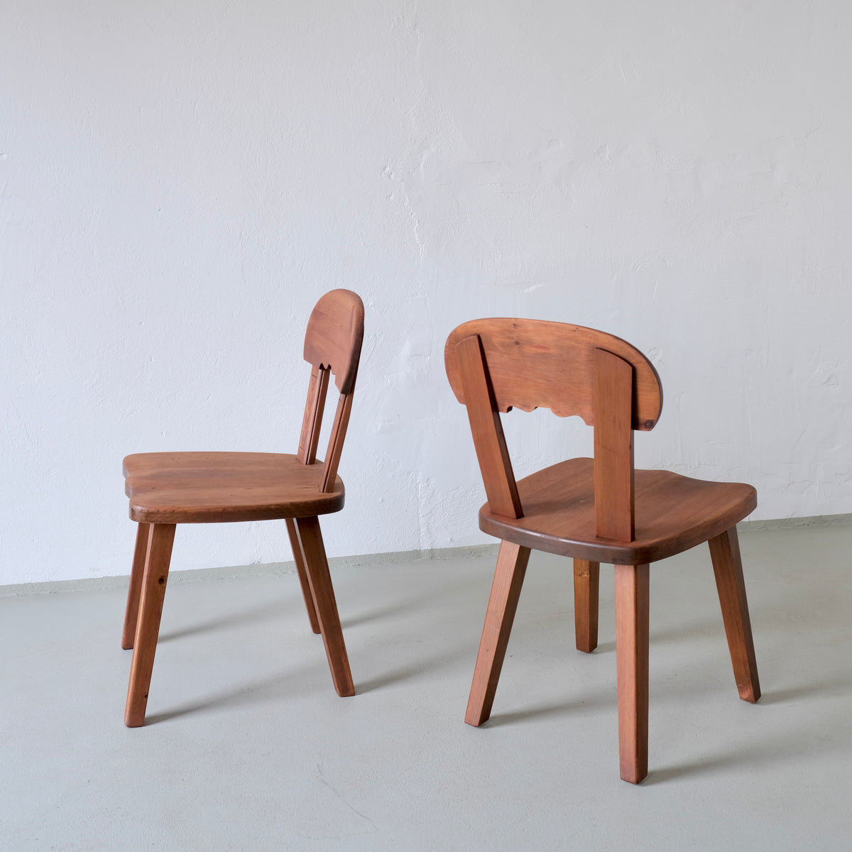 Two vintage Swedish pine chairs showing rustic carved backrests
