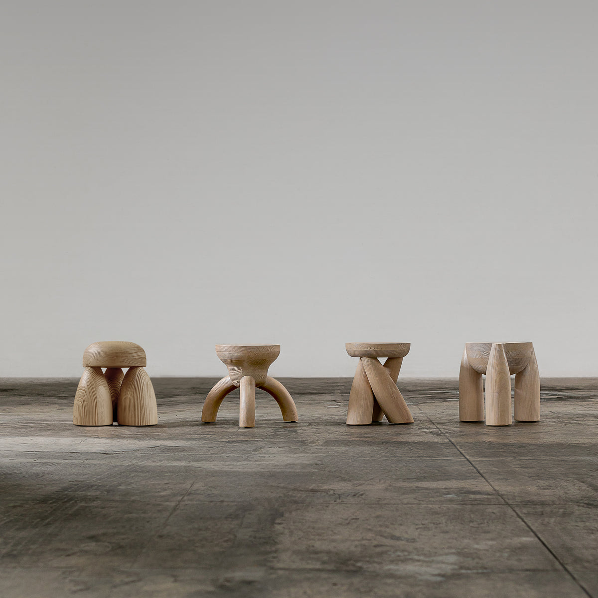 ELEMENTOS Set of Stools, sandblasted pine with black finish by Daniel Couttolenc — back view highlighting unique leg designs