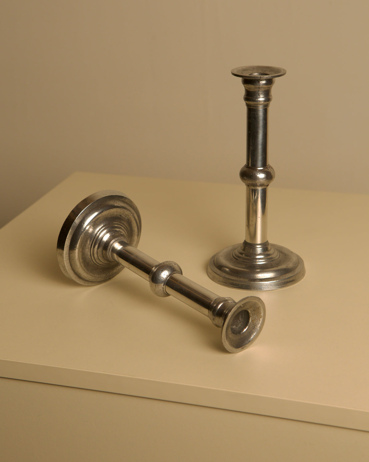 Pair of Italian Metal and Aluminum Candleholdersc80s — angled view on light-colored surface