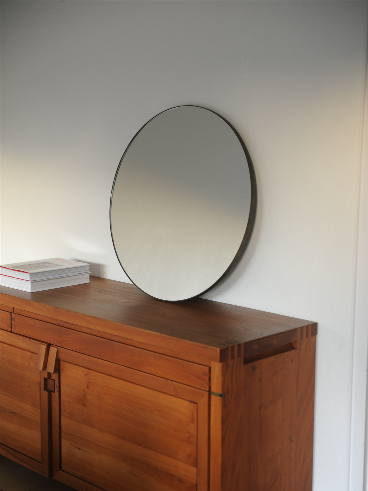 Mid-century circular mirror with black frame on teak sideboard