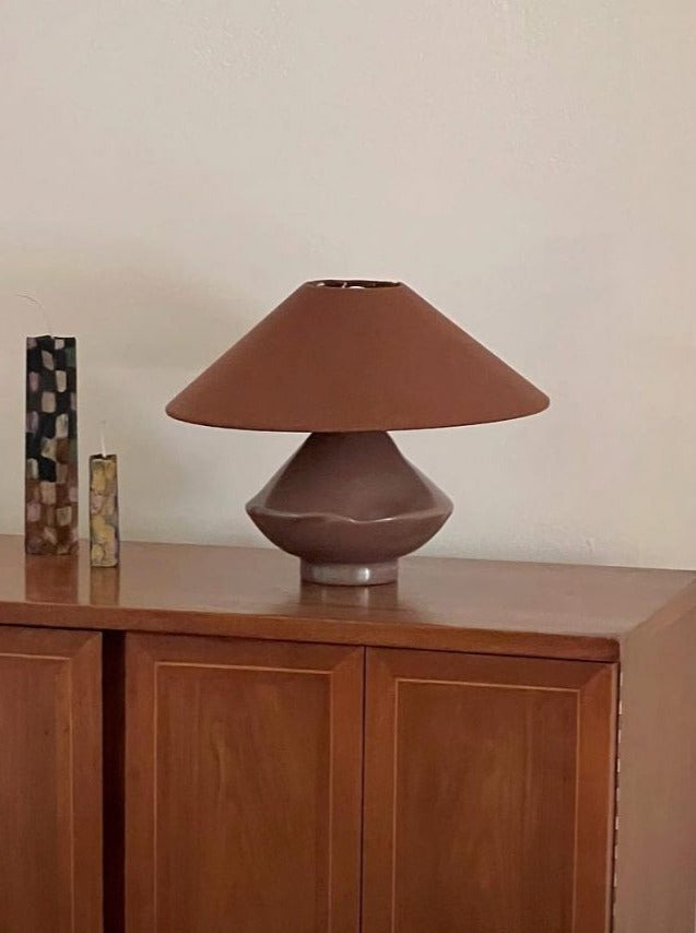Brown conical glass table lamp styled on walnut sideboard