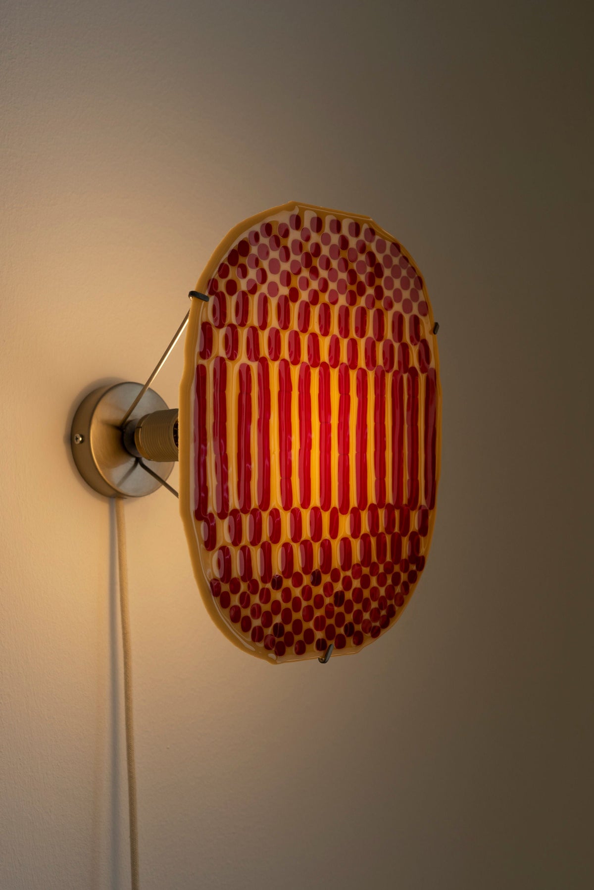 Illuminated profile view of Beige Checker wall lamp, red dotted glass panel