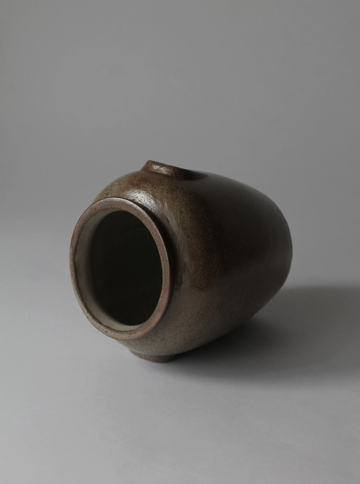 Brown ceramic vase lying on side showing opening and texture