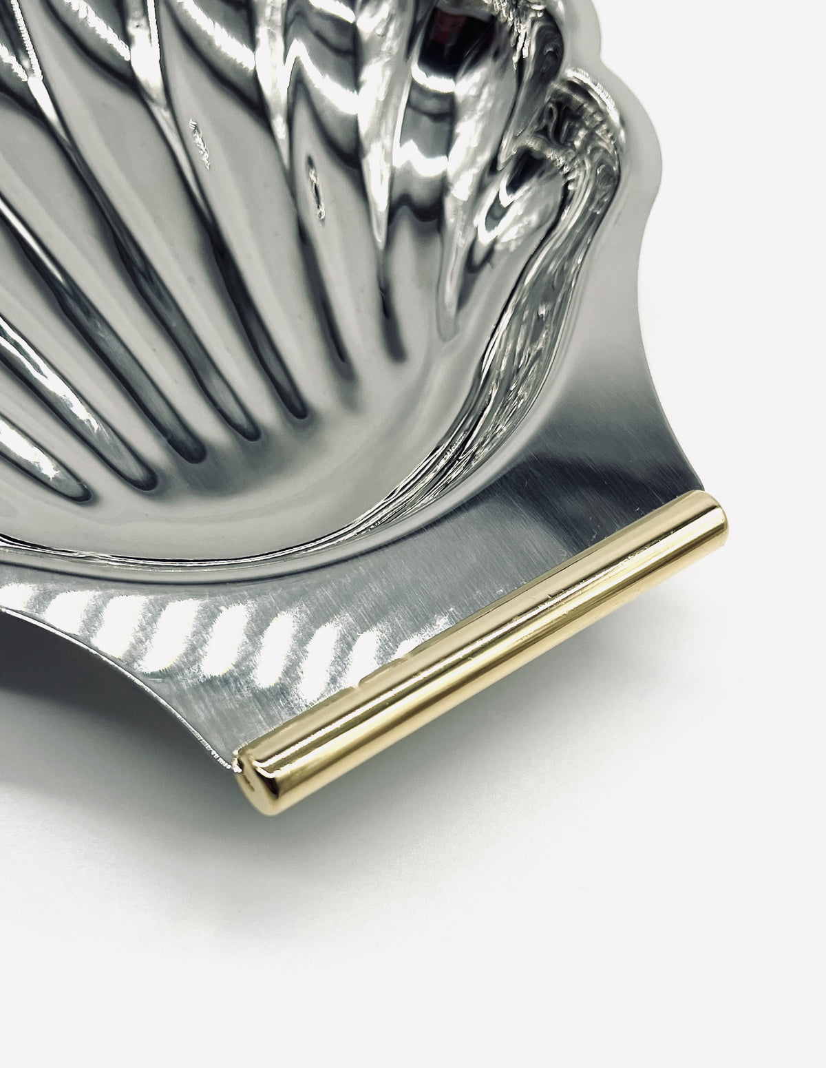 Stainless steel shell dish detail showing gold-trimmed edge