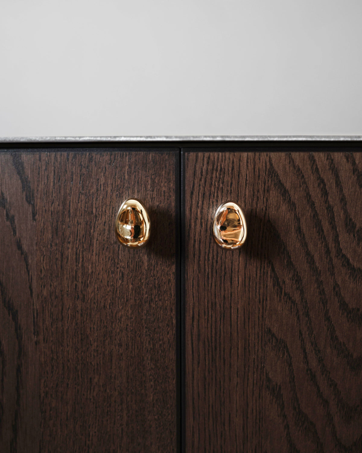 Rud Knob - Brass — close-up of brass knob on dark wood cabinet